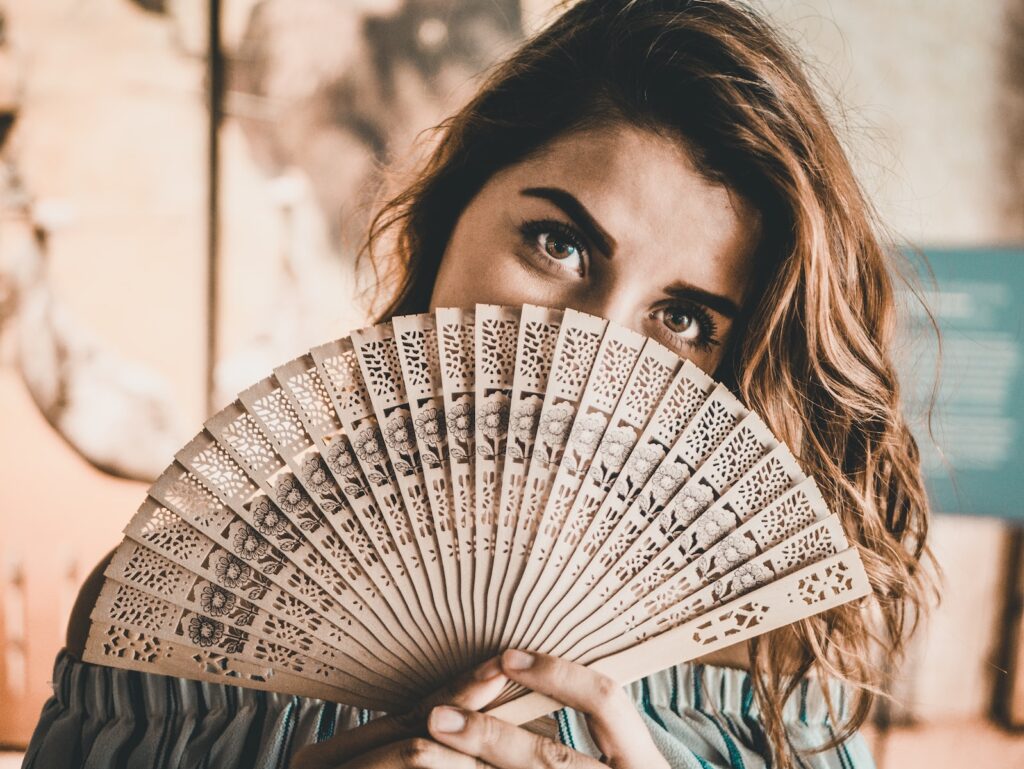 photography of woman holding brown hand fan